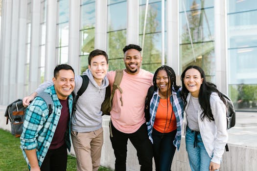 A diverse group of young adults smiling and standing together in front of a modern glass building.
